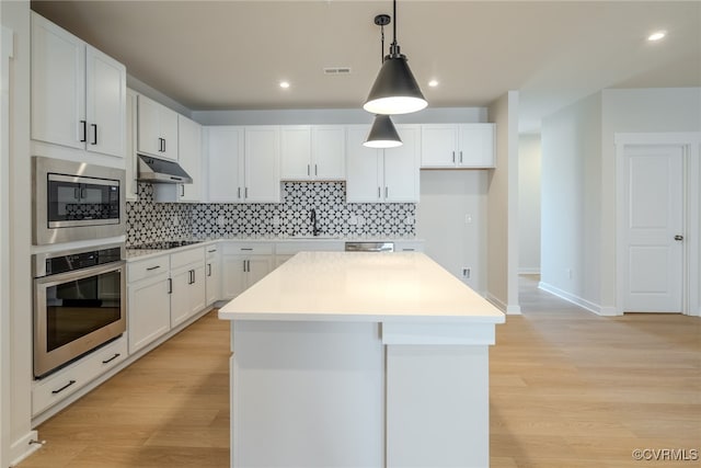 kitchen with light hardwood / wood-style flooring, stainless steel appliances, a center island, and white cabinets