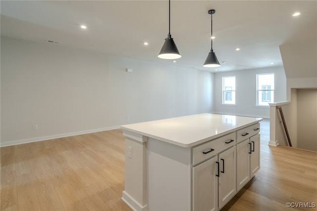 kitchen with light hardwood / wood-style floors, white cabinets, hanging light fixtures, and a kitchen island