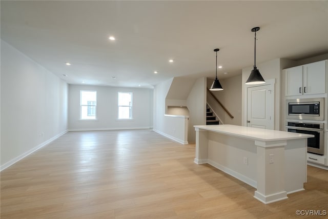 kitchen featuring a center island, decorative light fixtures, white cabinetry, appliances with stainless steel finishes, and light hardwood / wood-style floors