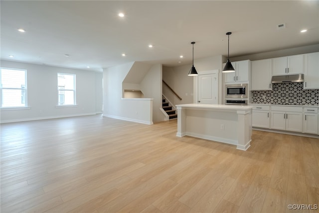 kitchen featuring a kitchen island, appliances with stainless steel finishes, decorative light fixtures, and light hardwood / wood-style floors