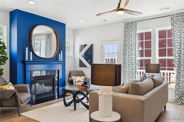 living room with light hardwood / wood-style floors, ceiling fan, and a healthy amount of sunlight