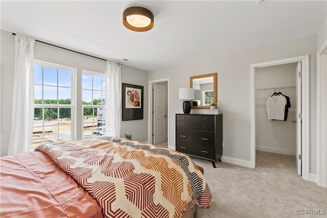 bedroom featuring light colored carpet, a spacious closet, and a closet