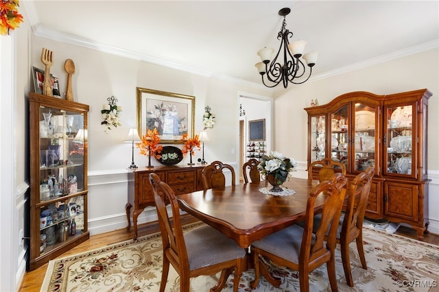 dining room featuring light hardwood / wood-style floors, an inviting chandelier, and ornamental molding