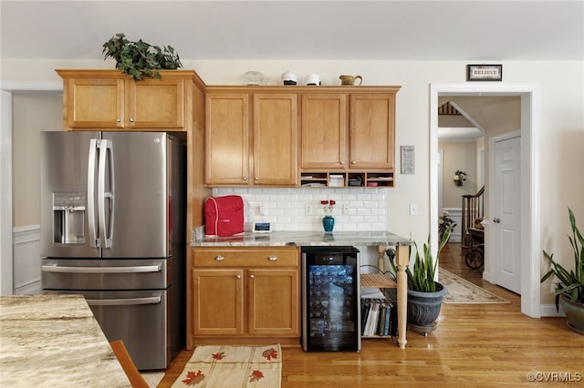 kitchen with wine cooler, light hardwood / wood-style flooring, light stone counters, and stainless steel fridge