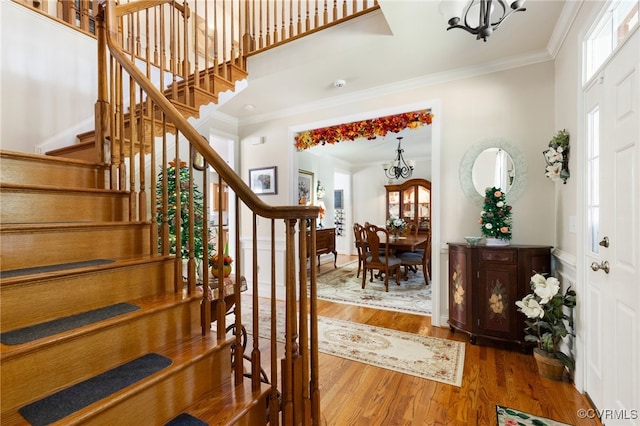 entryway featuring a notable chandelier, wood-type flooring, and ornamental molding