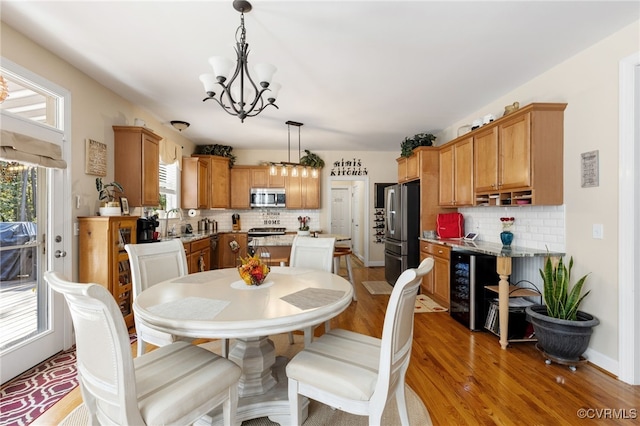 dining area with a healthy amount of sunlight, wood-type flooring, sink, and a chandelier