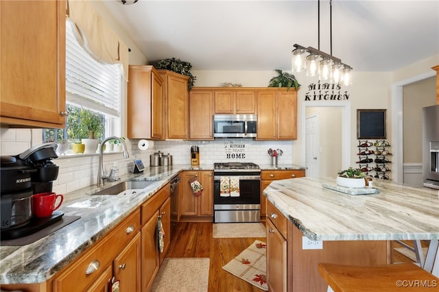 kitchen with sink, appliances with stainless steel finishes, dark hardwood / wood-style floors, and a kitchen island