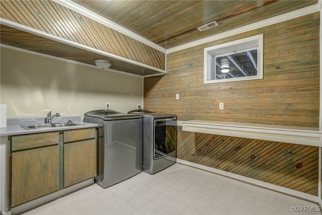 washroom with sink, crown molding, washing machine and dryer, and wood walls