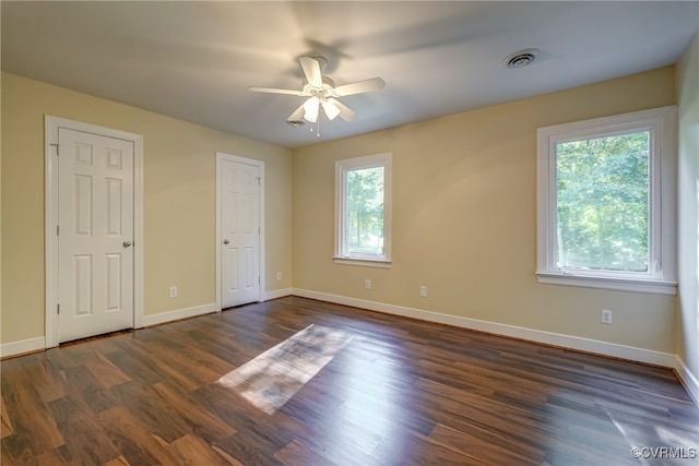 unfurnished bedroom featuring dark wood-type flooring, ceiling fan, and multiple windows