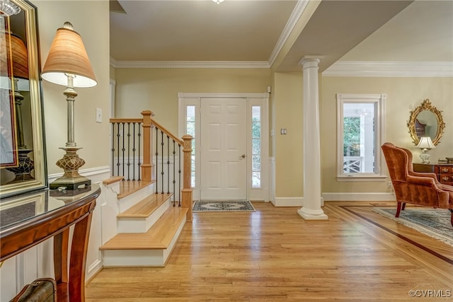 entryway featuring crown molding, decorative columns, and light wood-type flooring