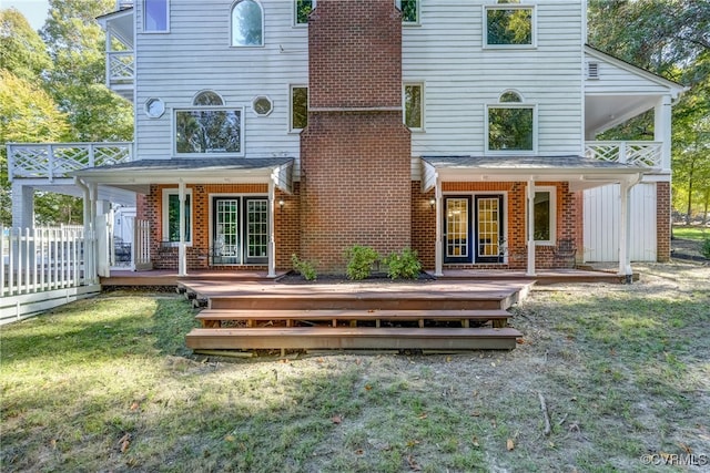 back of house with a deck and a lawn