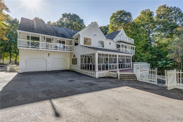 rear view of property featuring a garage and a sunroom