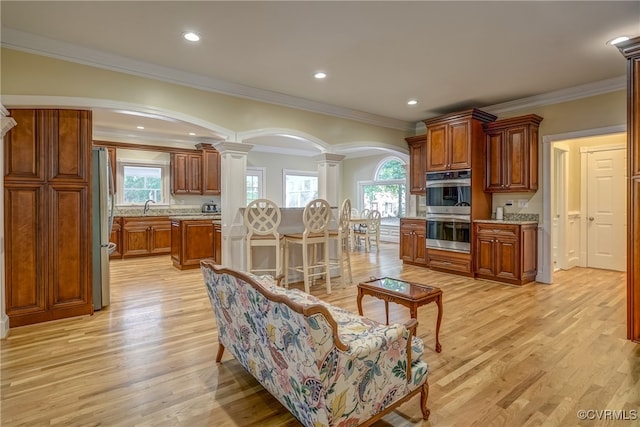 living room featuring a healthy amount of sunlight, ornamental molding, and light hardwood / wood-style flooring