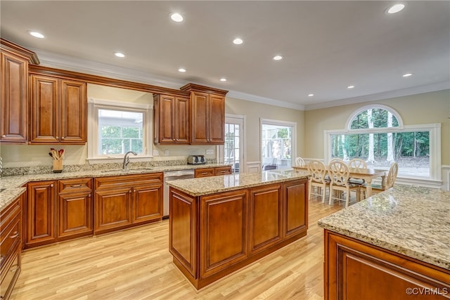 kitchen featuring dishwasher, sink, light stone countertops, a center island, and light hardwood / wood-style floors