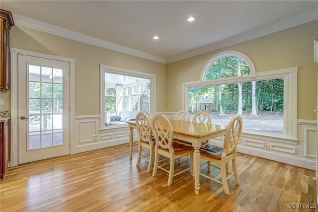 dining space with light hardwood / wood-style floors, crown molding, and a wealth of natural light