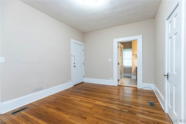 unfurnished bedroom featuring wood-type flooring and ensuite bathroom