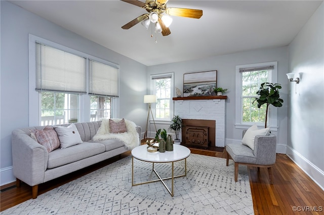 living room featuring a fireplace, wood-type flooring, and ceiling fan