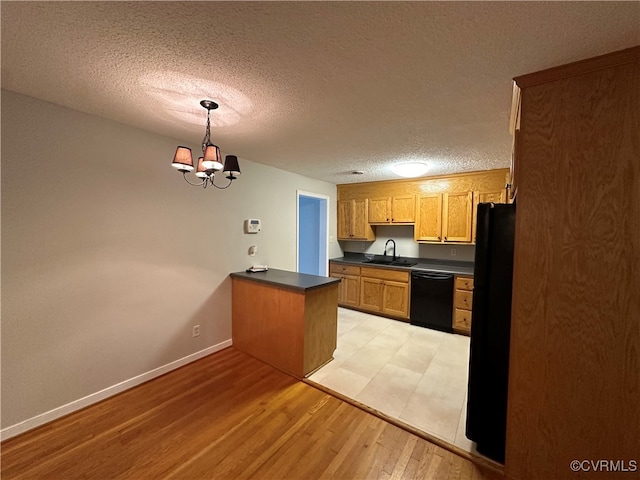 kitchen with black appliances, light wood-type flooring, a notable chandelier, a textured ceiling, and decorative light fixtures