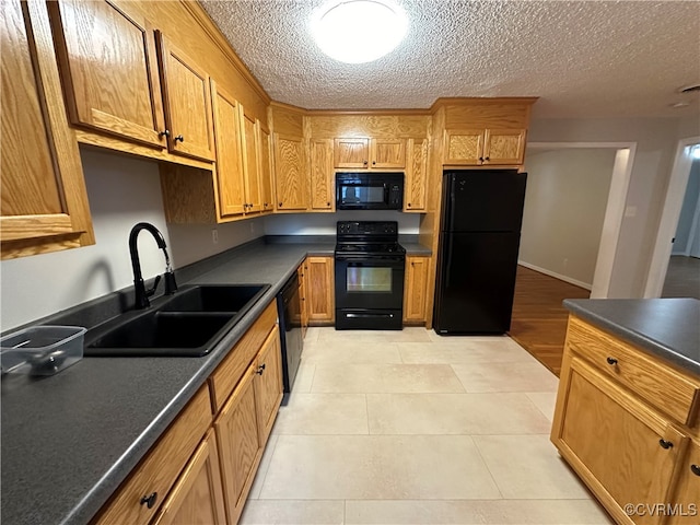 kitchen with a textured ceiling, black appliances, light tile patterned floors, and sink