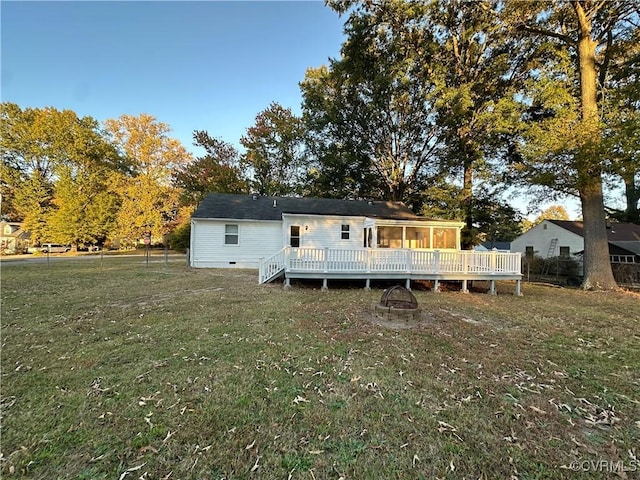 back of house featuring an outdoor fire pit, a deck, and a yard