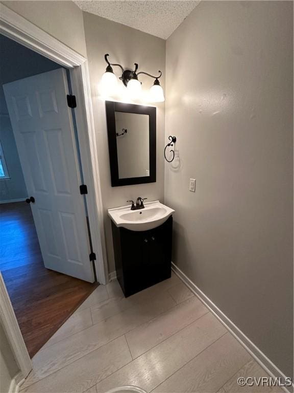 bathroom with a textured ceiling, vanity, and wood-type flooring