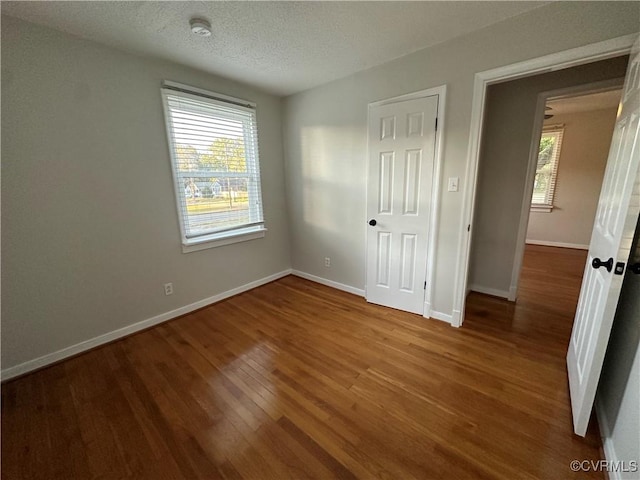 unfurnished bedroom with a closet, a textured ceiling, and hardwood / wood-style floors