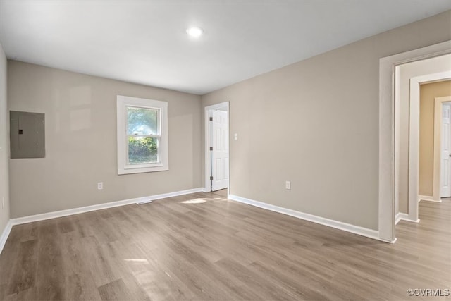 spare room with electric panel and light wood-type flooring