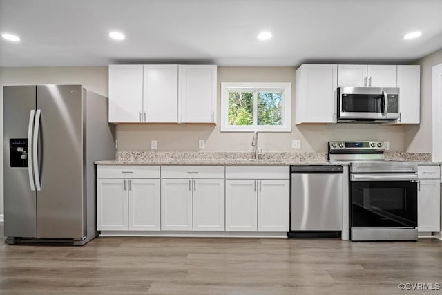 kitchen with appliances with stainless steel finishes, light wood-type flooring, and white cabinetry