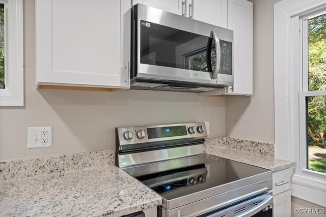 kitchen with appliances with stainless steel finishes, white cabinetry, and plenty of natural light