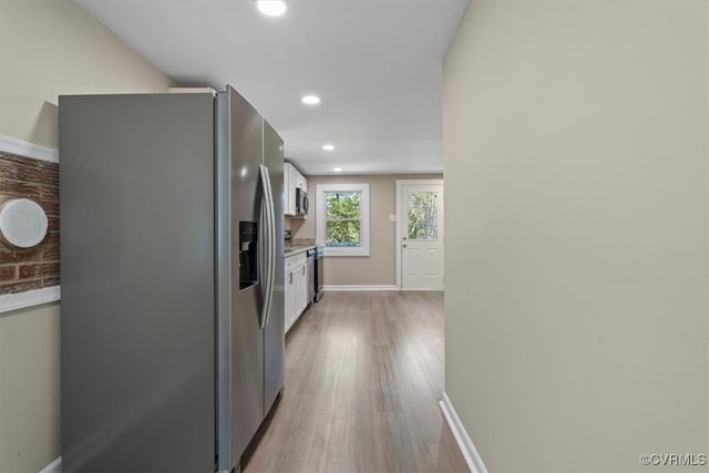 kitchen featuring appliances with stainless steel finishes, light hardwood / wood-style flooring, and white cabinets