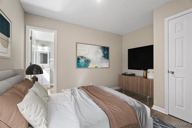 bedroom with ensuite bath and dark hardwood / wood-style flooring