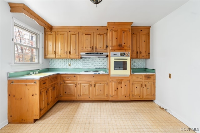 kitchen featuring white appliances, tasteful backsplash, and sink