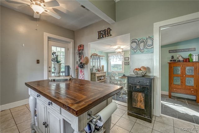 kitchen featuring a wealth of natural light, butcher block countertops, light tile patterned flooring, and ceiling fan