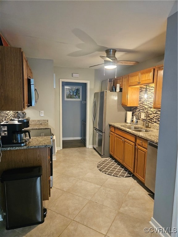 kitchen featuring light stone countertops, sink, backsplash, ceiling fan, and stainless steel appliances