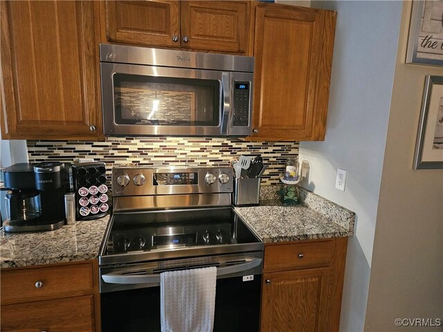 kitchen with appliances with stainless steel finishes, tasteful backsplash, and light stone countertops