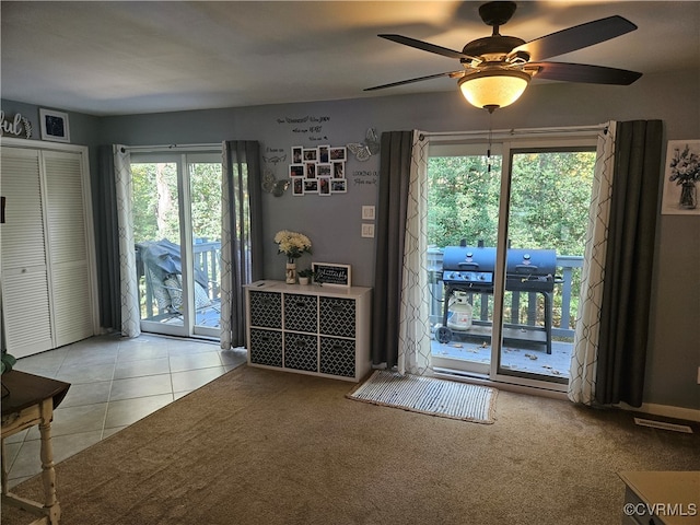 doorway featuring ceiling fan and light tile patterned floors