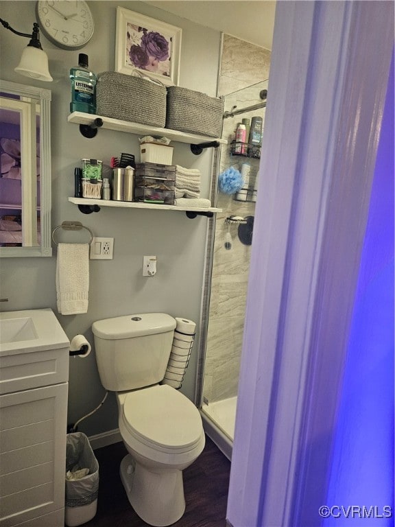 bathroom featuring toilet, hardwood / wood-style floors, walk in shower, and vanity