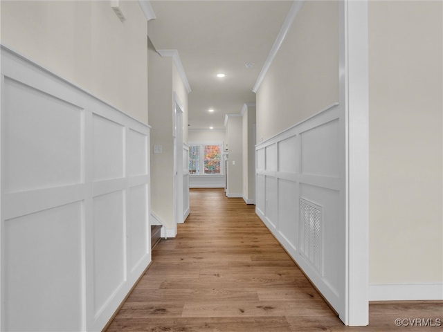 hall with light hardwood / wood-style floors and crown molding