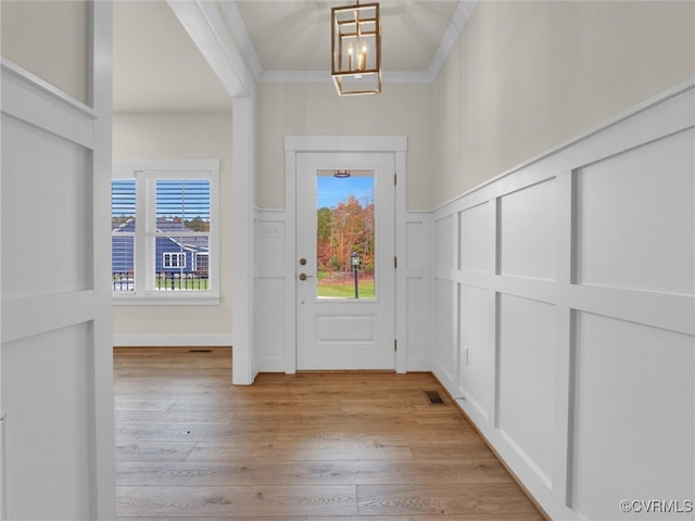 foyer featuring crown molding, plenty of natural light, light hardwood / wood-style floors, and a notable chandelier