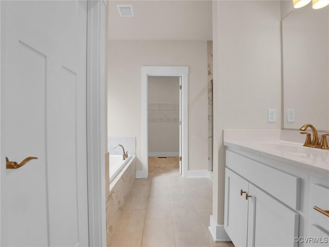 bathroom featuring tile patterned flooring, vanity, and a relaxing tiled tub