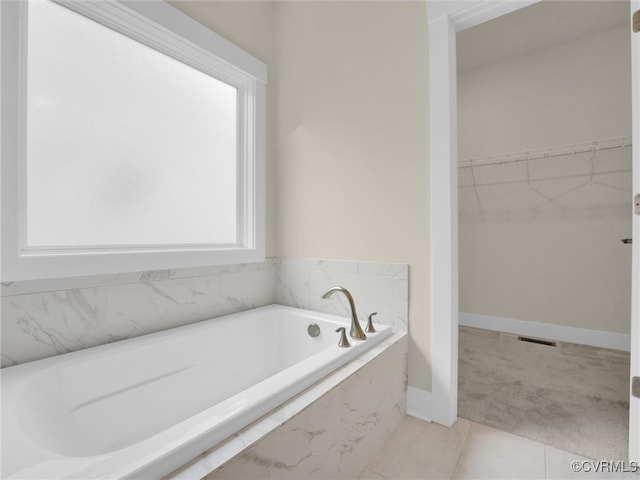 bathroom featuring plenty of natural light, a relaxing tiled tub, and tile patterned flooring