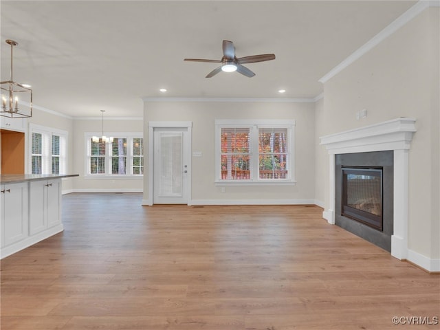 unfurnished living room with ceiling fan with notable chandelier, light wood-type flooring, and ornamental molding