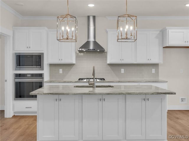 kitchen with white cabinets, wall chimney exhaust hood, stainless steel appliances, and decorative light fixtures