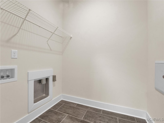 washroom with washer hookup and dark tile patterned flooring