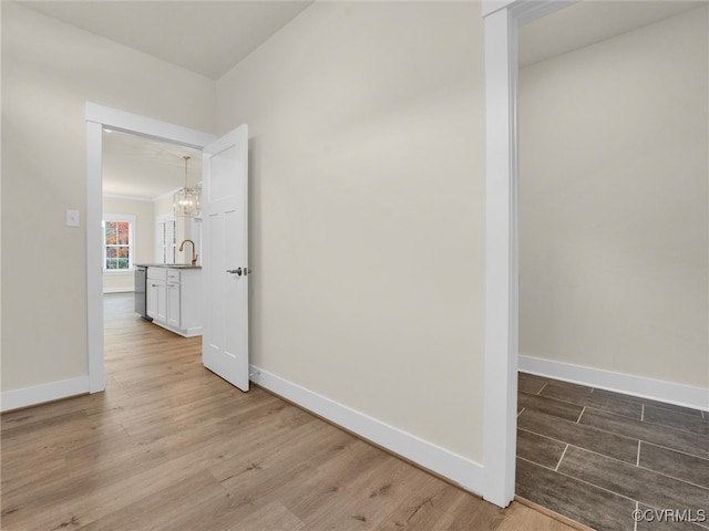 hall featuring sink, light hardwood / wood-style flooring, and a notable chandelier