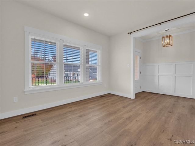 spare room with a chandelier, light hardwood / wood-style floors, and ornamental molding