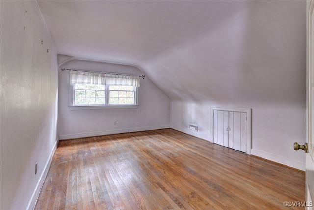 additional living space featuring vaulted ceiling and wood-type flooring