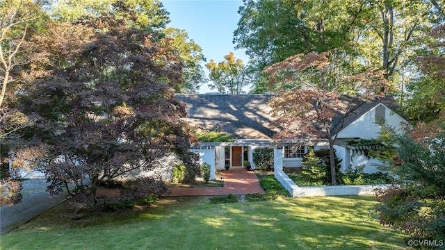 view of property hidden behind natural elements featuring a front yard