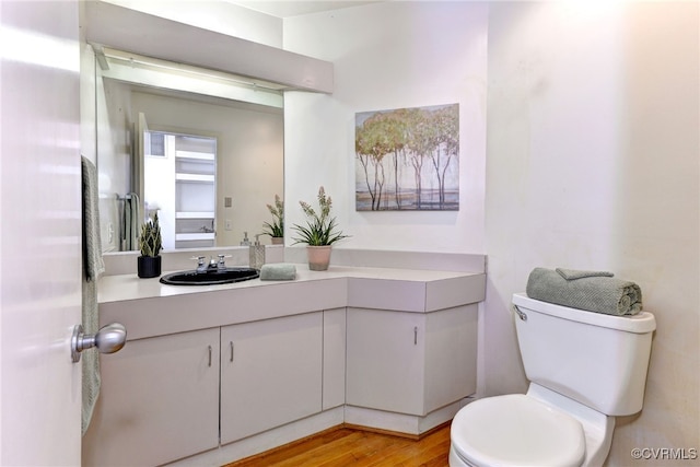 bathroom with toilet, a healthy amount of sunlight, hardwood / wood-style flooring, and vanity