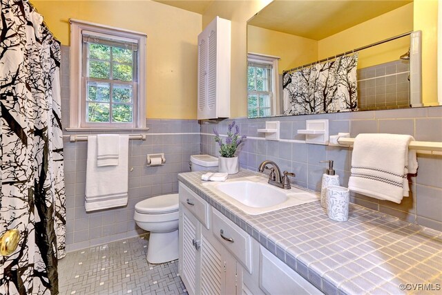 bathroom featuring vanity, toilet, tile patterned floors, and tile walls